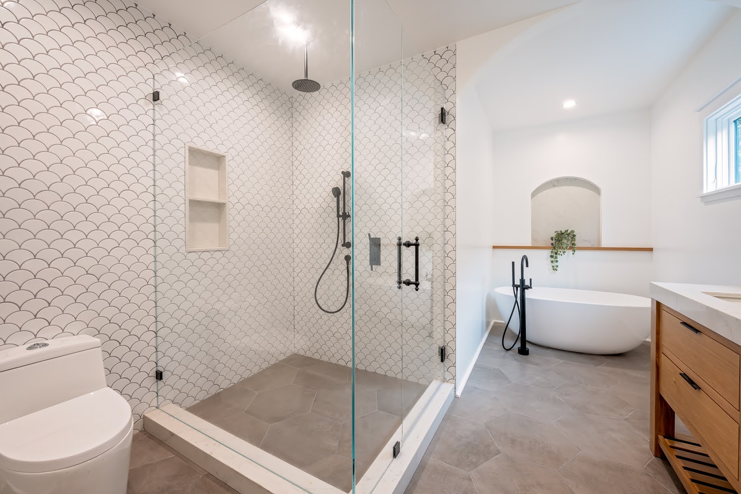Lillian Master Bathroom — glass shower with scallop tile, built-in niche and black fixtures, freestanding tub beyond